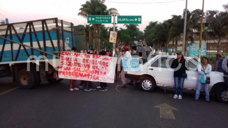 Padres de familia cuyos hijos estudian de la escuela Secundaria Técnica Agropecuaria número 125 de la cabecera municipal de Comapa, bloquearon el tramo carretero de Huatusco-Conejos a la altura de la entrada a este municipio de Comapa, en protesta porque les pretenden quitar una parcela de 5 has. 